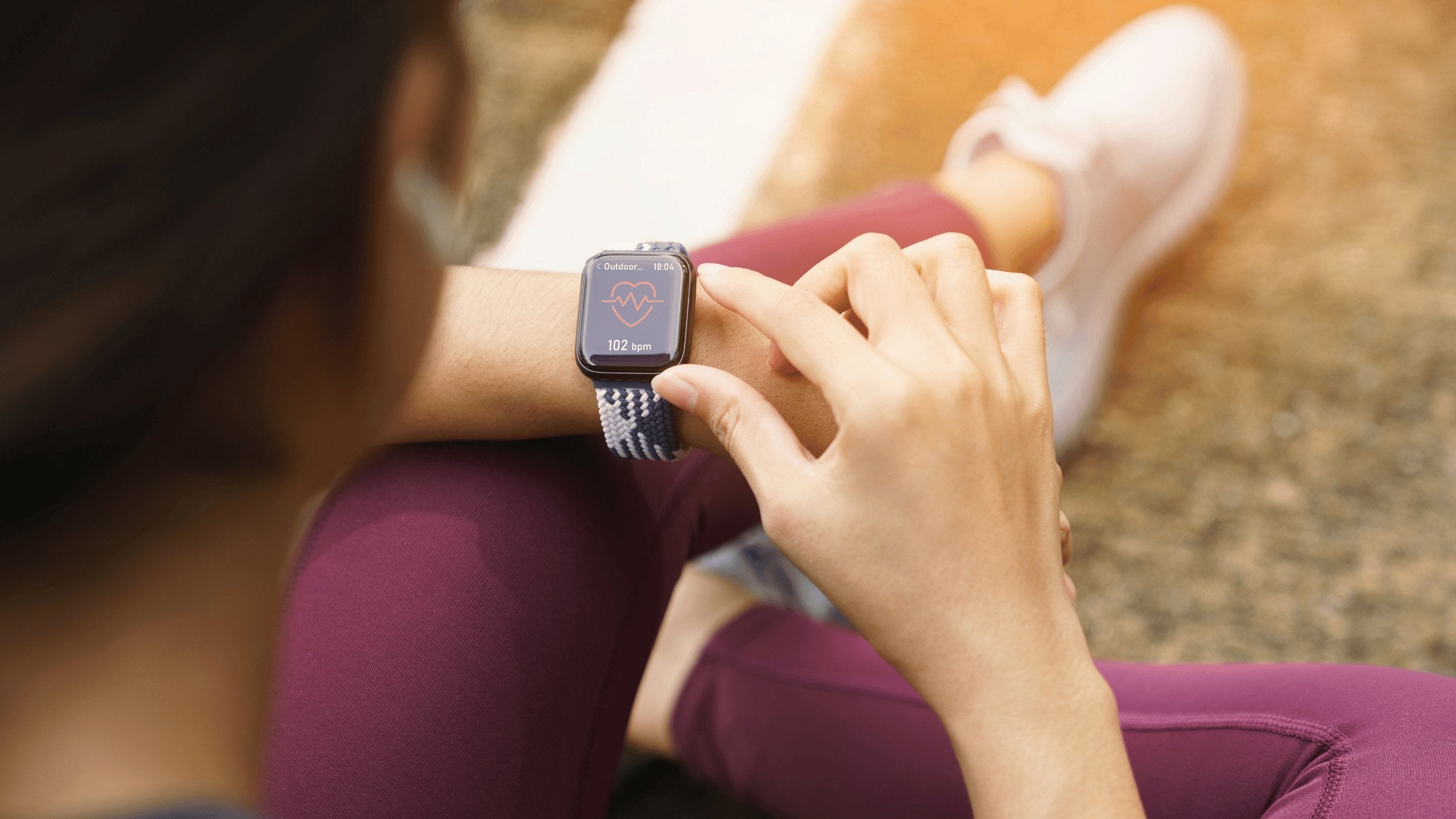 woman on grass with smart watch